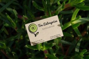 carte de visite avec logo représentant une plante qui pousse en forme de spirale de couleur noire et verte sur fond de papier recyclé
